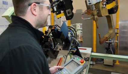 Robot technician using teach pendant to program robot.