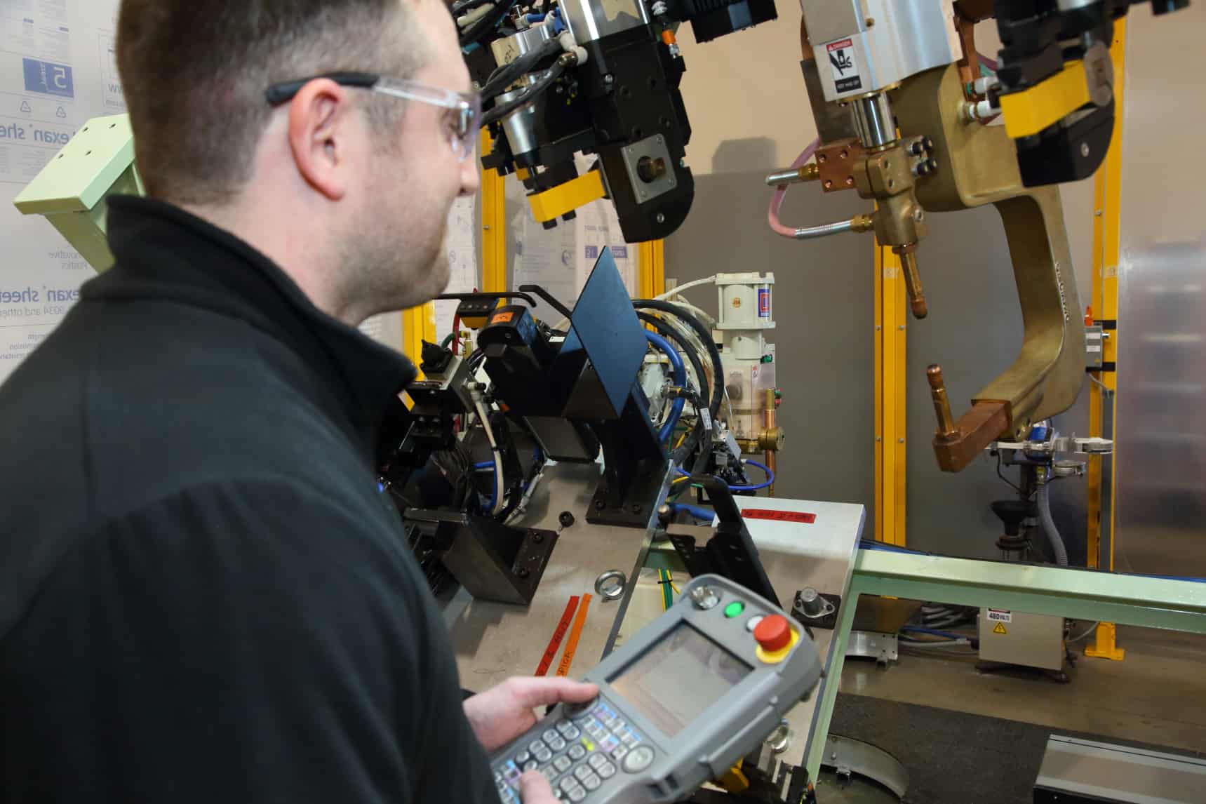 Robot technician using teach pendant to program robot.